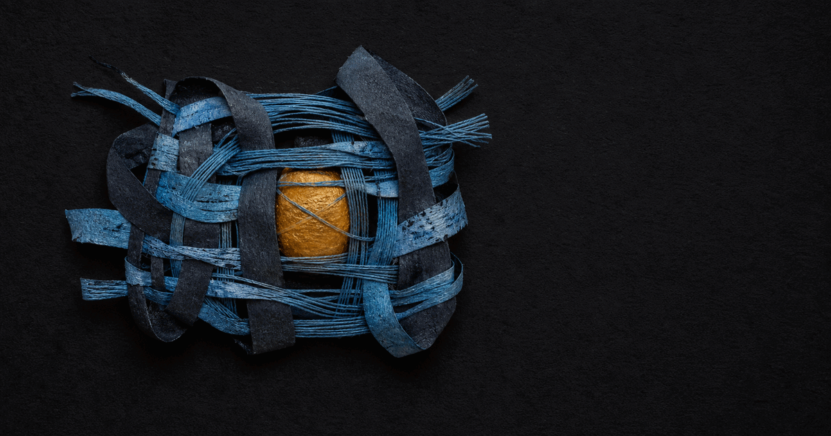 Hand-woven blue and slate ribbons cradling a small amber core